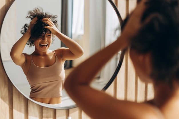 happy-woman-styling-her-afro-hair-front-mirror-home 695242-24105